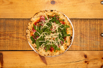 Large thin crust Italian pizza with arugula, prosciutto, grated Parmesan cheese cooked in a stone oven