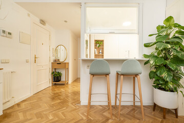 Living room and promenade area of a house with some wooden stools upholstered in blue fabric next to a serving hatch window