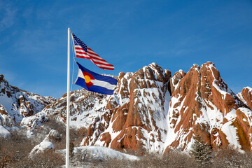 US flag in front of red rock formation at Roxborough State Park in Colorado in winter
