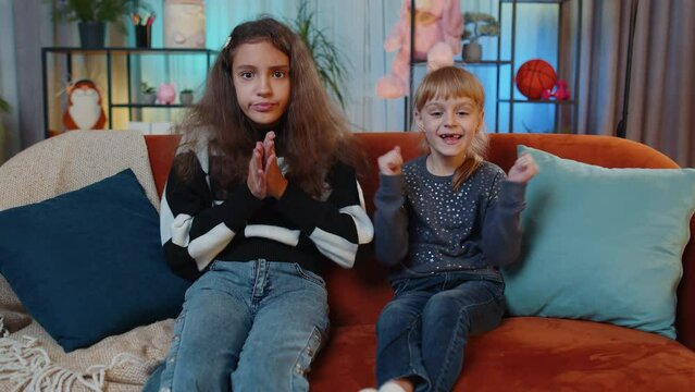 Teenage child and little sister kid girls shouting, celebrating success triumph, winning, goal achievement, good news, lottery jackpot luck. Female siblings children or best friends at home play room
