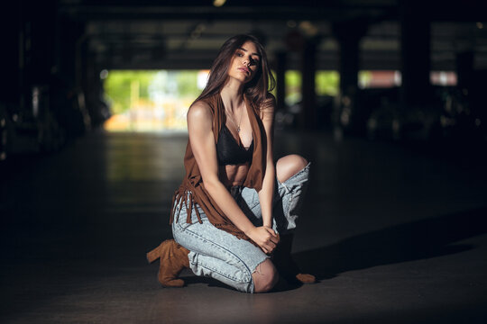 Young girl in jeans poses in an underground garage