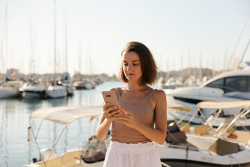 Beautiful woman in talking on the phone against the backdrop of the blue sea and yachts