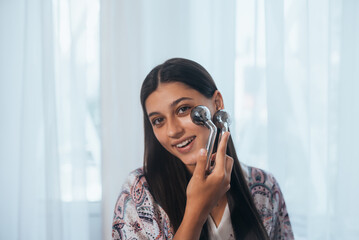 Woman massaging her cheek with massage Y-shaped ball roller.