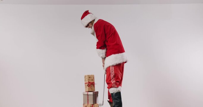 Terrible Santa Jake forcefully plays golf with a stack of Christmas presents.