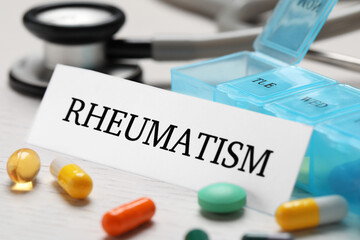 Obraz premium Sheet of paper with word Rheumatism and many different pills on white wooden table, closeup