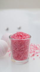 Glass with sea salt and bath bombs on table in bathroom