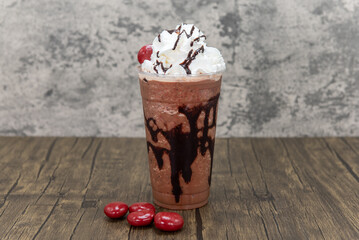 Chocolate flavored latte in a very all drinking cup and topped with whipped cream and chocolate covered cherries