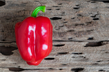 Red sweet pepper on wood table close up.