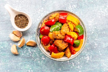 Food healthy stir fried chicken add sweet peppers in bowl on blue wood table.