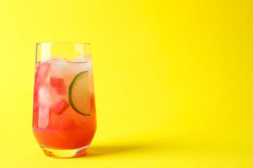 Tasty summer watermelon drink with lime in glass on yellow background. Space for text