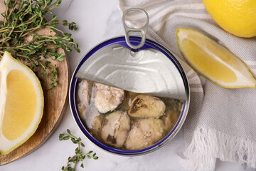 Open tin can with mackerel chunks, lemon and thyme on white marble table, flat lay