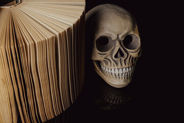 Human skull and old book on mirror table