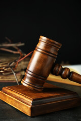 Wooden judge gavel and crown of thorns on black table, closeup