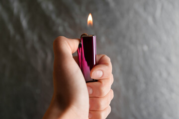 Woman holding pink lighter on grey background, closeup