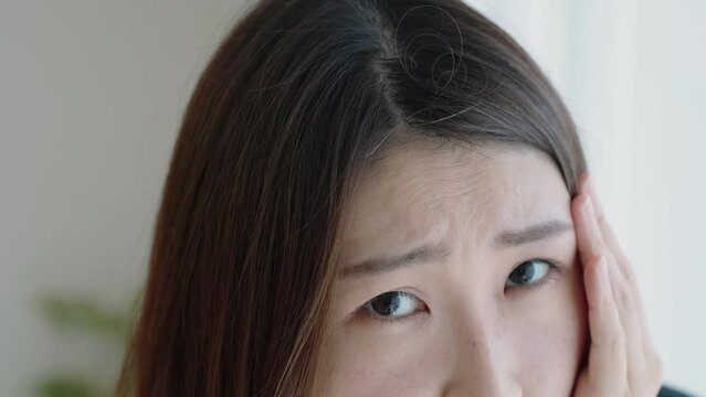 髪の毛の生え際をチェックする女性（プリン髪・ハゲ）