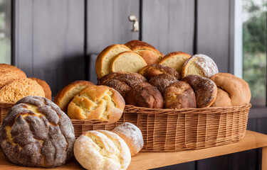 wicker basket of fresh baked bread over a counter, bakery product display, assortment of baked bread