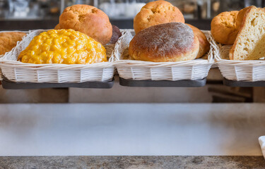 Bread on a white wicker basket over a counter, bakery product display, assortment of baked bread