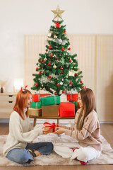 Obraz na płótnie Canvas Christmas concept, Two women wearing deer horn and exchanging gift box with happiness together