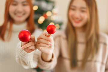 Fototapeta na wymiar Christmas concept, Two women wears reindeer horns and holding red christmas ball for decoration