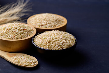 Organic Thai brown rice grain in bowl on black background, Asian healthy food ingredients