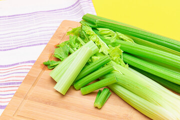 Fresh Celery Stem and Chopped Celery Sticks on Wooden Cutting Board. Vegan and Vegetarian Culture. Raw Food. Healthy Diet with Negative Calorie Content. Slimming Food