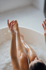 Fototapeta premium Pretty young woman taking bath at home back view