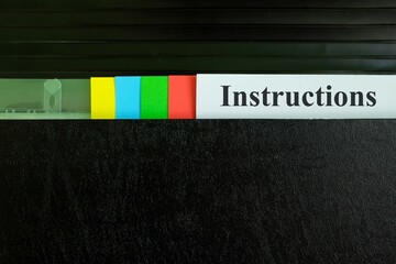 Hand picking instructions file record in black binder folder. Work instruction concept.	