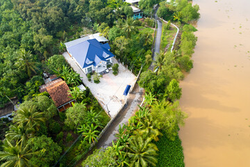 aerial view of Villa house in the middle of the garden with blue tile roof and the river at Mekong...