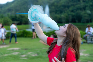 Cheerful woman eating sweets in park with green mountain background