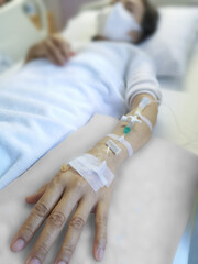 Asian woman patient receiving chemical drugs on drip to blood vessel solution to treat cancer.