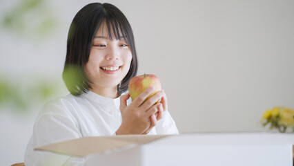 ダンボールからりんごを取り出す女性（通販・お取り寄せグルメ）