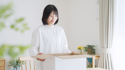 ダンボールを開ける女性（引越し・梱包）