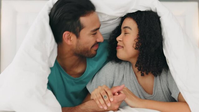 Happy, love and couple with a smile in bed relaxing, bonding and resting together at their home. Happiness, joy and loving young man and woman lying in the bedroom at house or hotel in Puerto Rico.