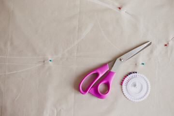 Sewing accessories on fabric pastel color. Process of creating clothes. Workplace of seamstress