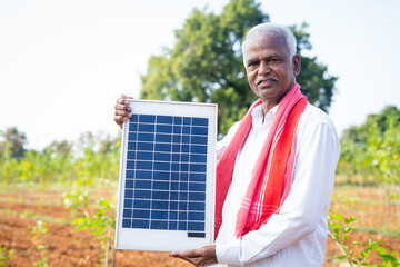 Confident indian farmer showing solar panel by looking at camera - concept of advertisement,...