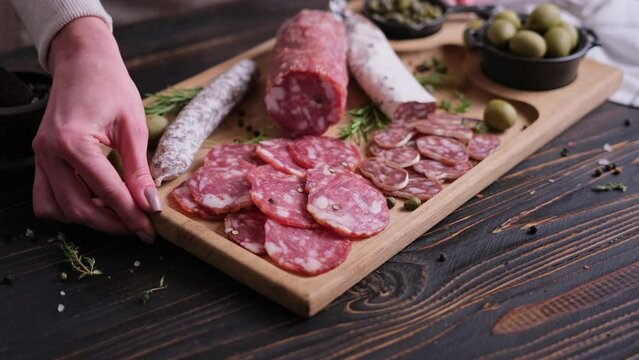 Woman putting wooden cutting board with Traditional Sliced fuet salami sausage