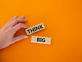 Think big symbol. Wooden blocks with words Think big. Beautiful orange background. Businessman hand. Business and Think big concept. Copy space.