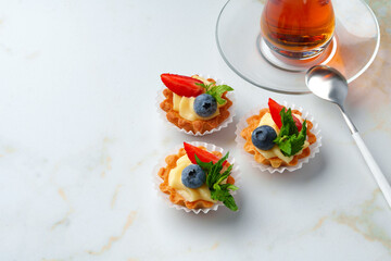 Tartalette with boiled milk cream and berries on white table