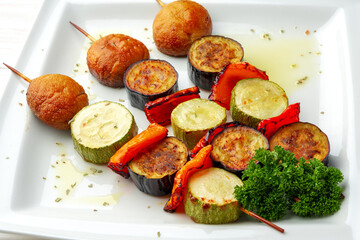 Grill vegetable kebabs on skewers in white plate
