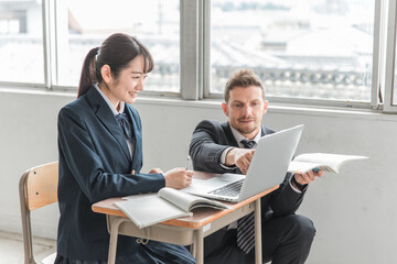 学校・塾でノートパソコンを使って勉強する高校生・中学生と外国人講師（ICT教育）
