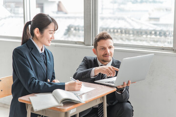 学校・塾でノートパソコンを使って勉強する高校生・中学生と外国人講師（ICT教育）
