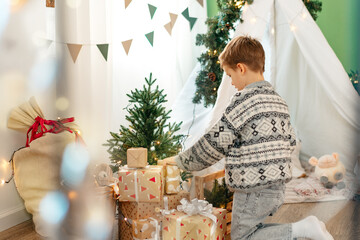 A little boy lying in a children's wigwam decorated for Christmas © fotofabrika