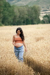 Naklejka na ściany i meble Pregnant young woman in wheat field