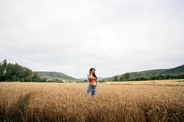 Naklejka na ściany i meble Pregnant young woman in wheat field