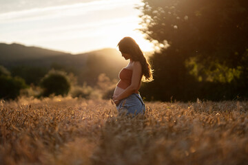 Pregnant young woman in wheat field - 551740570
