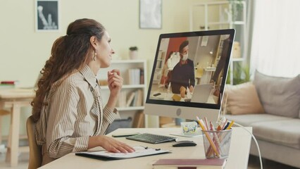 Successful young Caucasian businesswoman working from home video chatting with diverse office colleagues in face masks while discussing corporate project - Powered by Adobe