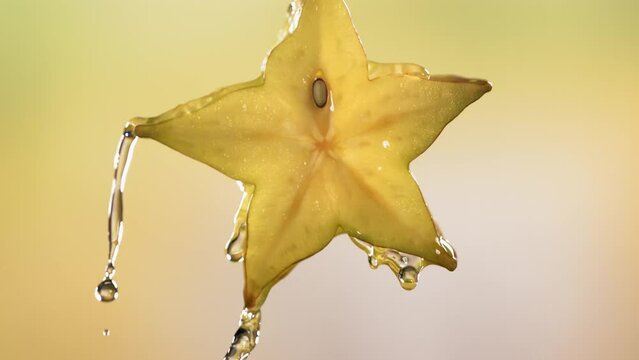 Slow Motion Macro Shot of Flowing Carambola Juice from Halved Carambola Star Fruit