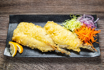 fish crispy tempura batter or breaded fish decorated julienned carrots, onions, cabbage and lemon on plate, Asian style