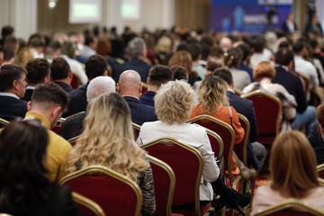 Shallow depth of field (selective focus) details with a crowd of people attending a conference...