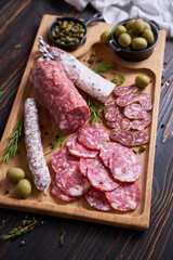 Traditional Spanish fuet salami sausage on wooden cutting board at domestic kitchen